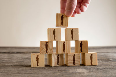 一个人用木块堆砌成的塔，里面有人的轮廓、人力资源和管理理念。